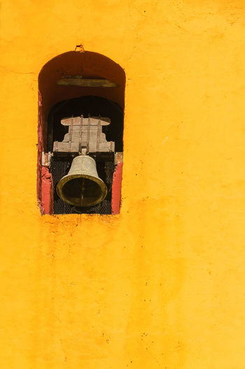 Low angle view of bell on yellow tower