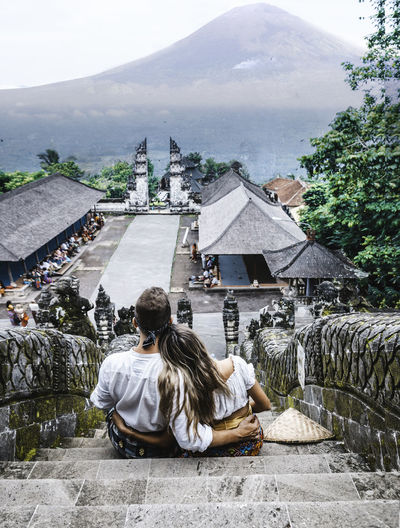 Rear view of people sitting on temple against mountains