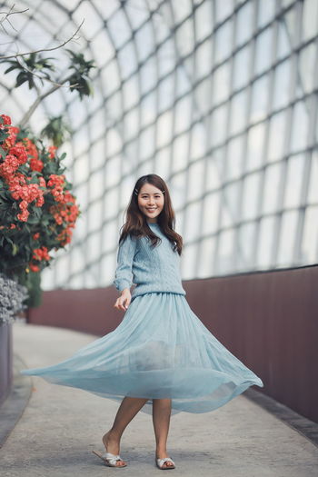 Portrait of cheerful young woman spinning in greenhouse