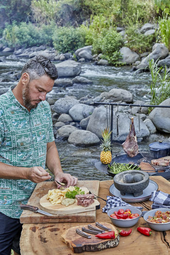 Chef preparing campsite picnic with wood fired grill and appetizers