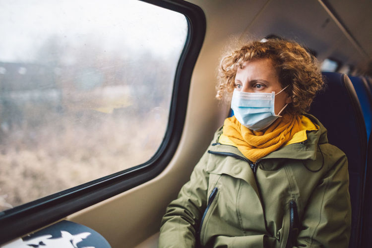 Woman wearing mask sitting in train