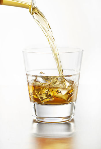 Liquor on the rocks pouring into tumbler
