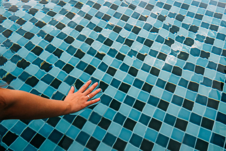 Cropped hand touching water in swimming pool