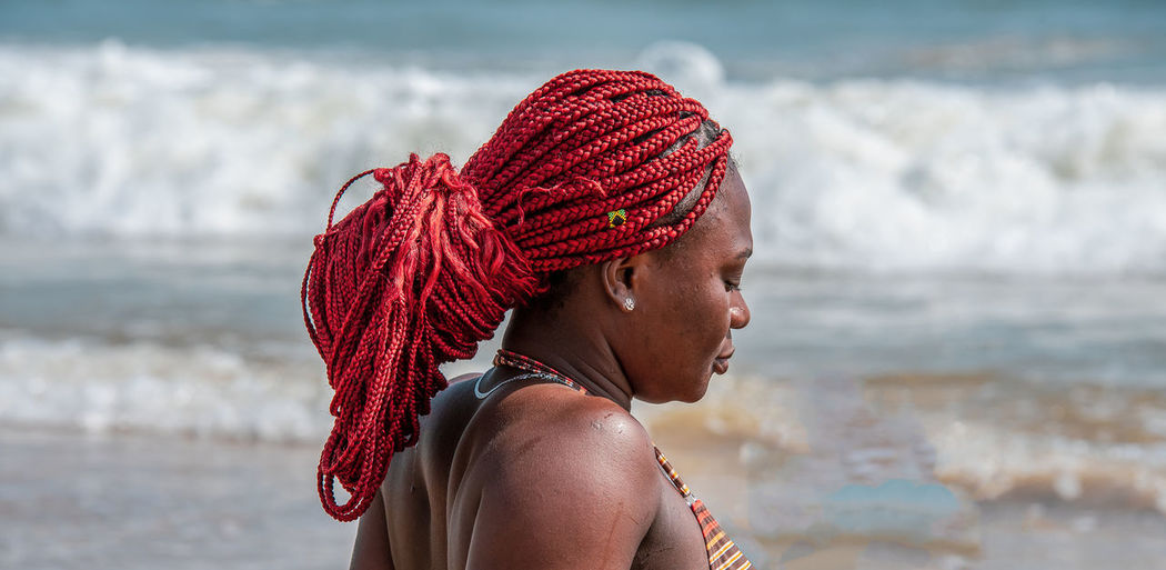 African woman with tied red rasta braided hair on a beach in ghana west africa