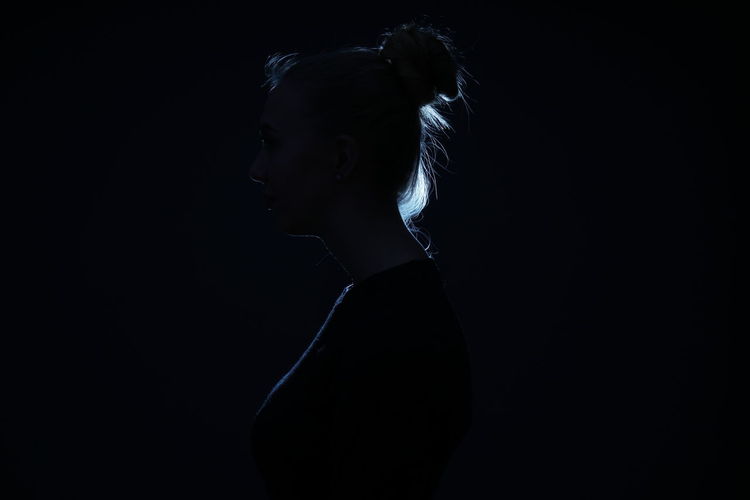 Portrait of young woman looking away over black background