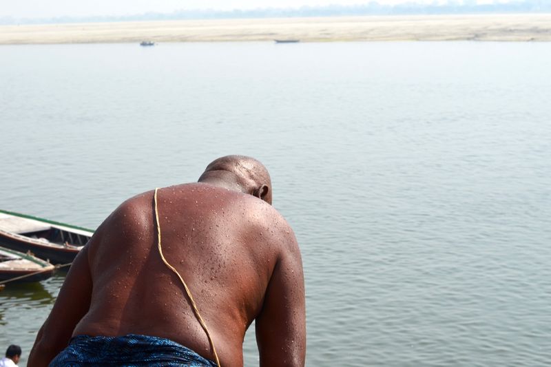 Rear view of shirtless man by sea