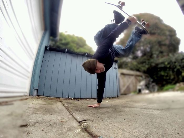 Full length of man performing stunt while skateboarding at driveway