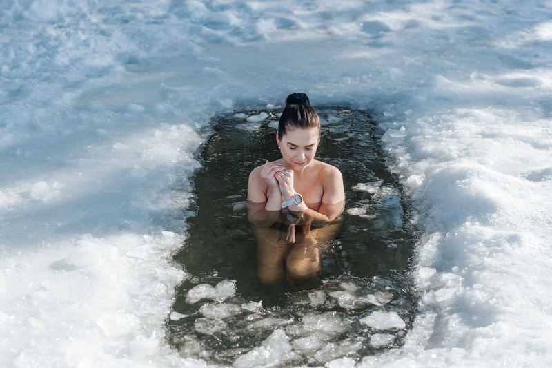 Woman sitting in frozen lake during winter