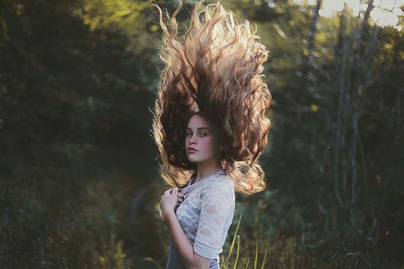 Portrait of woman tossing hair while standing outdoors