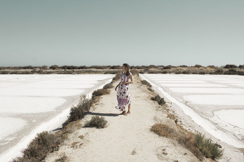 Rear view of woman walking on road against clear sky