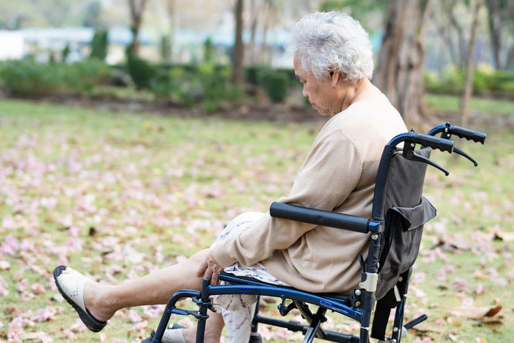 Senior woman sitting on wheelchair at park