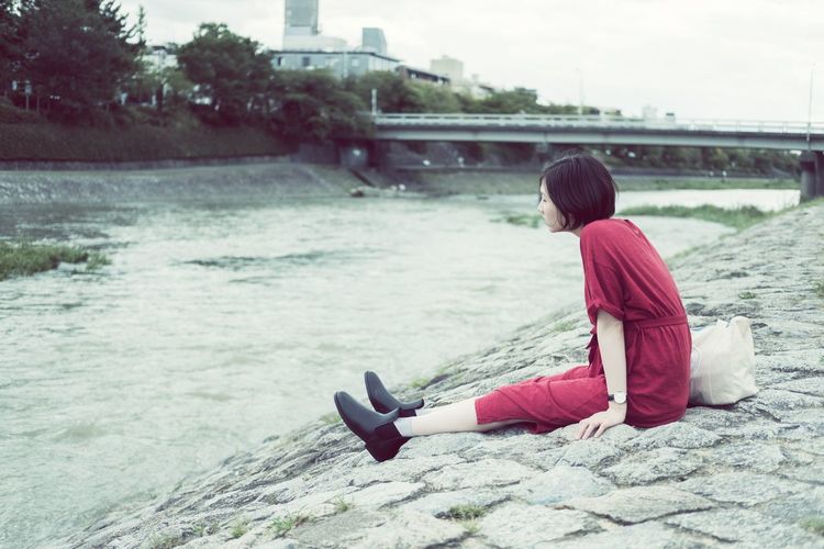 Rear view of woman sitting on riverbank