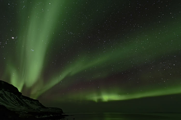 Low angle view of aurora borealis at night during winter