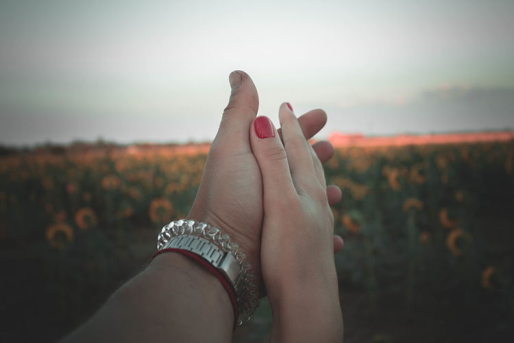 Cropped image of couple holding hands on field