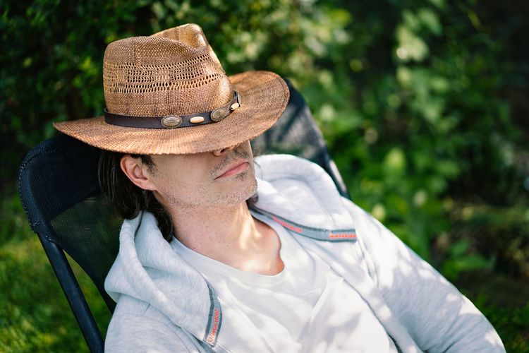 Man with straw hat relaxing on chair in the garden dunring summer