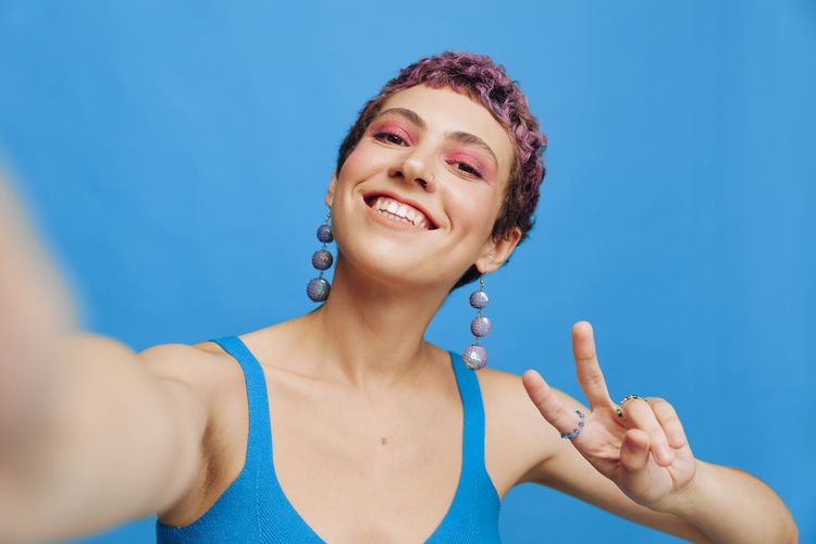 Portrait of young woman against blue background