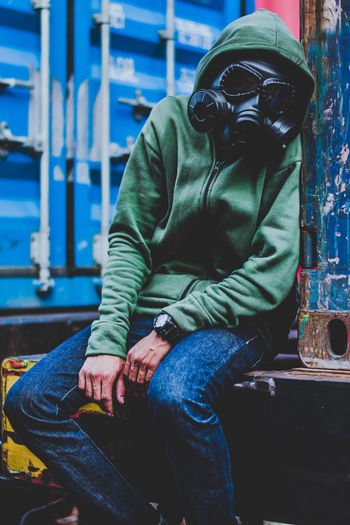 Man wearing gas mask while sitting outdoors