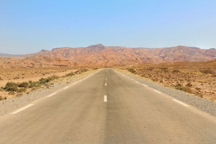 Empty road in desert against clear sky