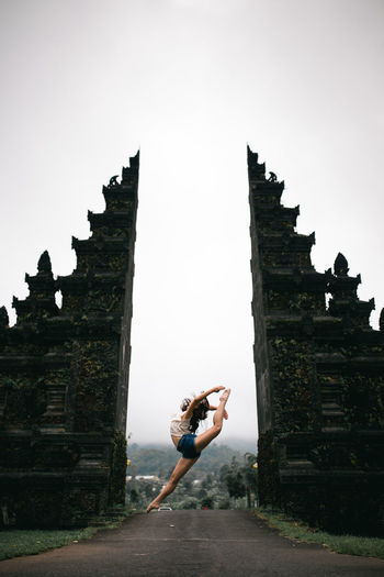 Low angle view of woman dancing in entrance against sky