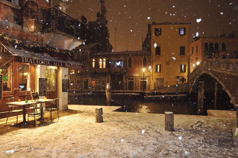 Illuminated buildings in city at night during snowfall