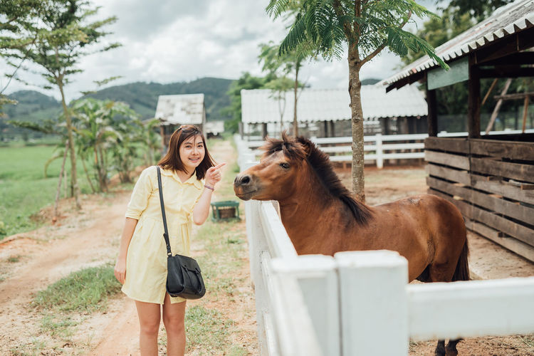 Woman pointing at horse by fence