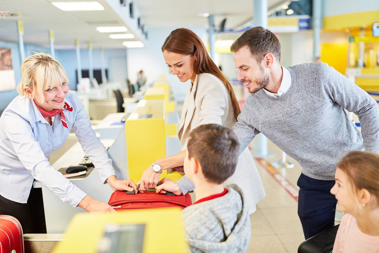 Parents with children standing at airport check-in counter