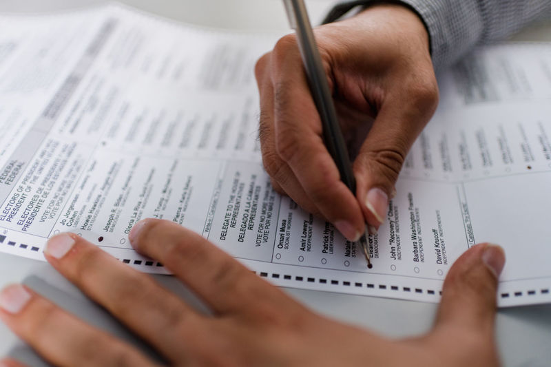 Close up of man's hands completing absentee ballot for election