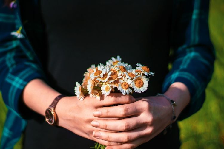 Midsection of woman holding white flowers