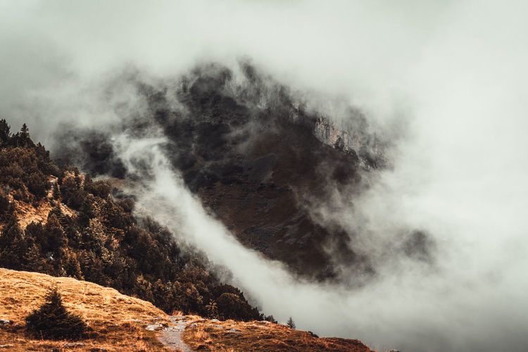 Smoke emitting from mountain against sky