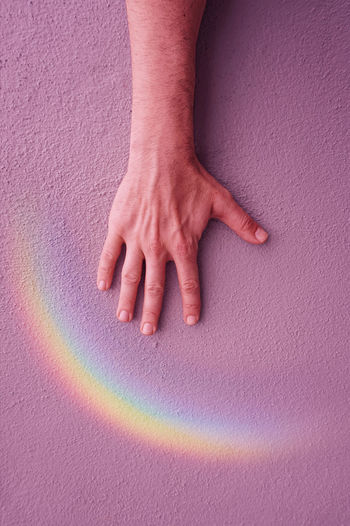 Hand with a rainbow on the pink wall. lgbt symbol