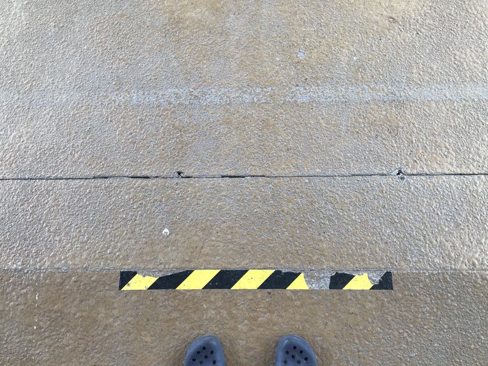 Low section of person standing on yellow road