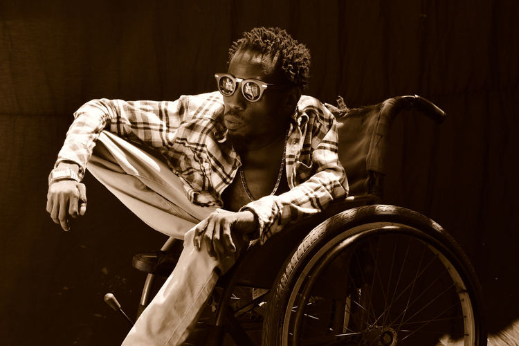 Disabled man wearing sunglasses while sitting on wheelchair