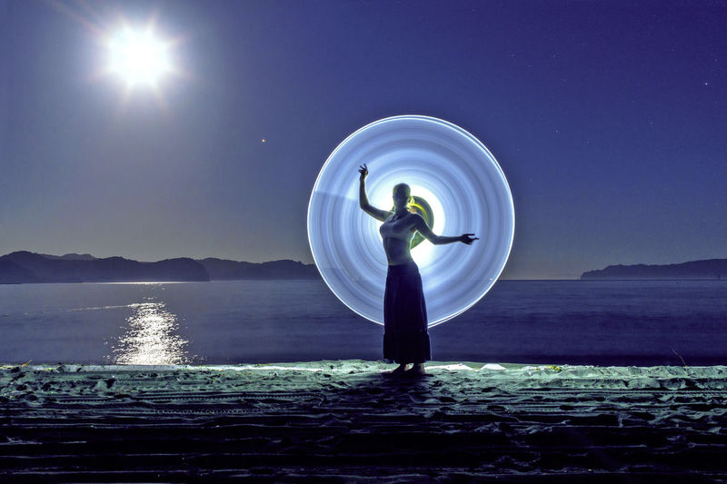 Young woman posing against light painting at beach