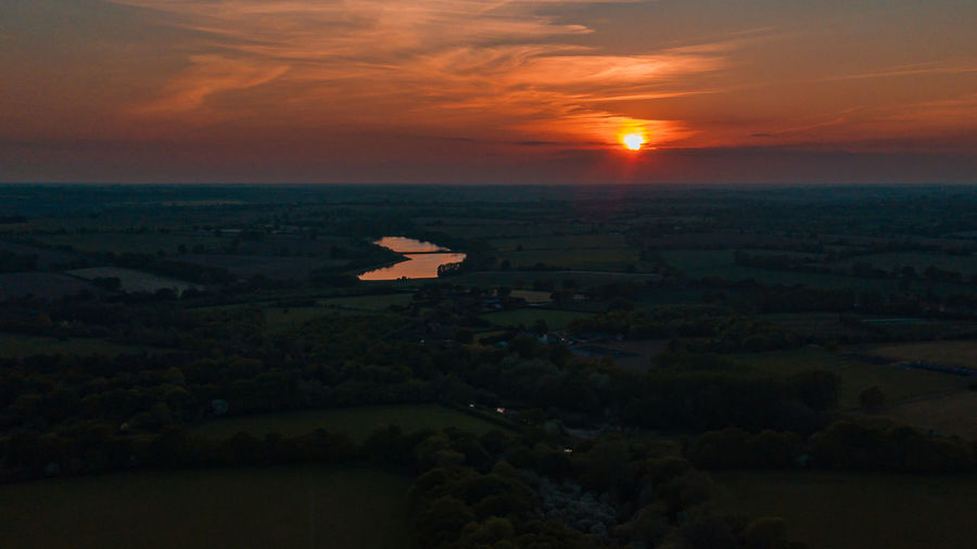 Scenic view of landscape against dramatic sky during sunset