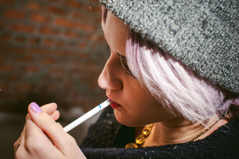 Close-up of young woman lighting cigarette