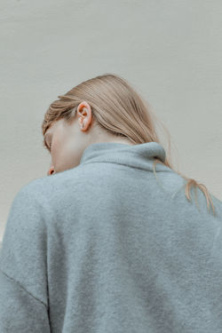 Portrait of young woman with eyes closed against wall