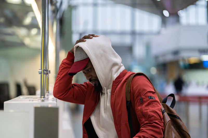 Frustrated sad young african man traveler missed flight standing at check-in area in airport