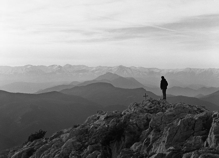Silhouette boy standing on mountain against sky
