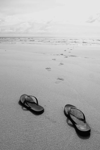 Flip-flop at beach against sky