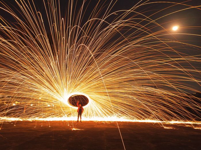 Man standing and play illuminated fire wool at night