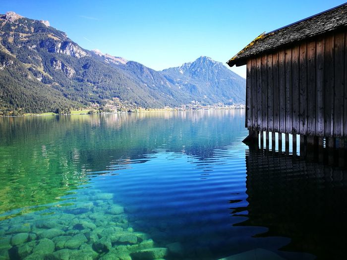 Scenic view of lake and mountains against clear blue sky
