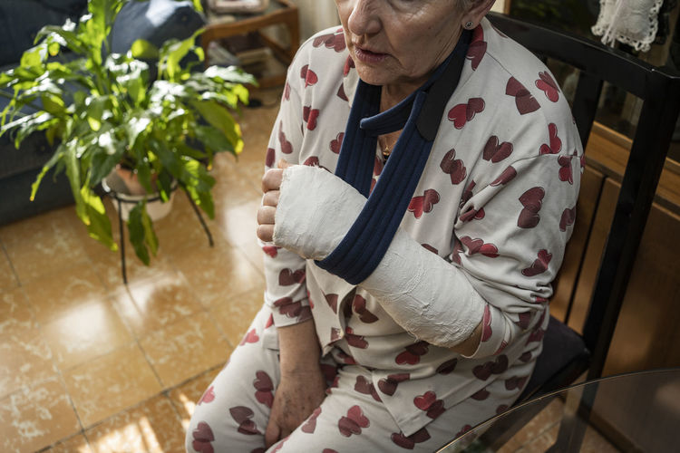 Caucasian adult woman with broken arm sitting at home