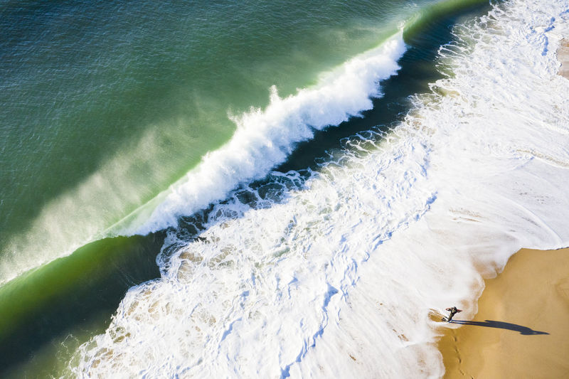 Bodyboard surfer watching shorebreak wave crashing on the beach aerial