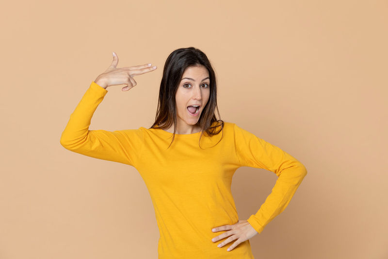 Portrait of woman standing against yellow background