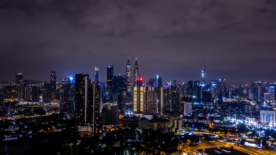 Illuminated buildings in city against sky at night