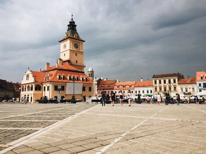Clock tower at brasov council square against cloudy sky