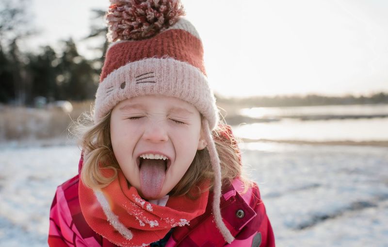 Young girl catching snow with her tongue out whilst playing outside