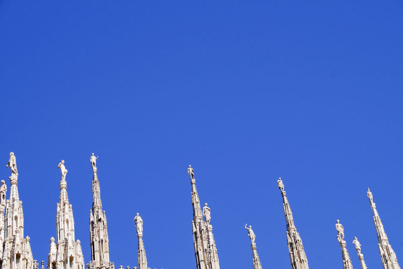 High section of duomo di milano against clear blue sky on sunny day