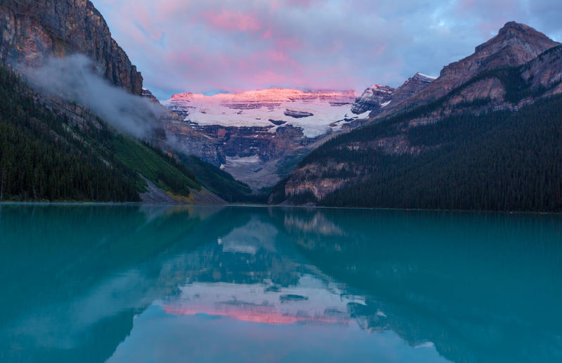 Scenic view of glacial lake and mountains during sunrise at banff national park