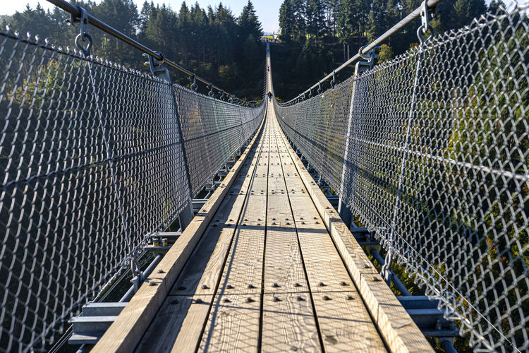 Suspension wooden bridge with steel ropes over a dense forest in west germany.